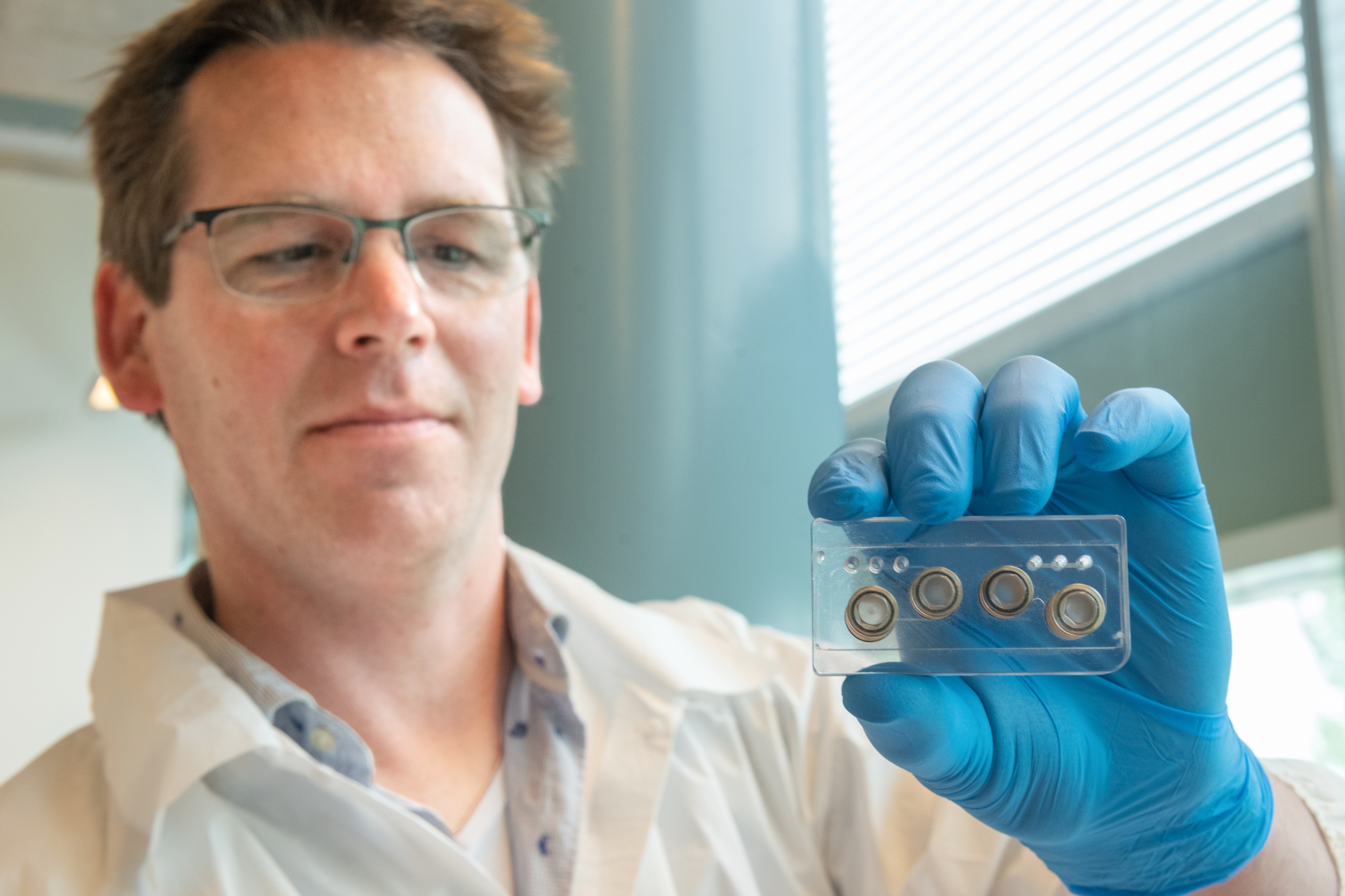 Portrait of Bas van Balkom with a multi-organ-on-chip in his hand